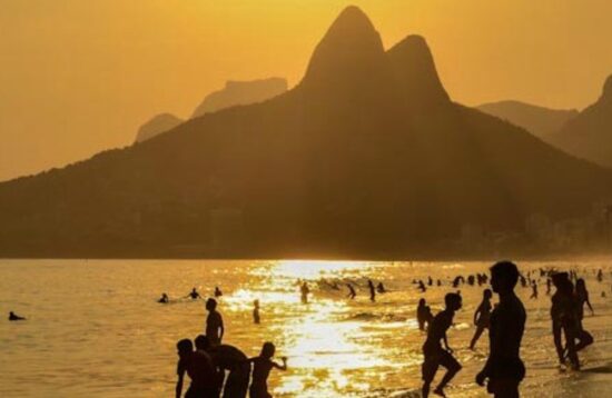 A vibrant sunset during a bike tour along the iconic beaches of Rio de Janeiro, with colorful skies over Ipanema and Copacabana. Silhouettes of cyclists enjoying the breathtaking view as the sun touches the horizon, with waves gently lapping against the shore